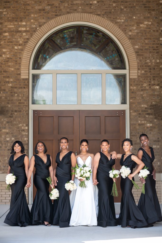 bridesmaids in black dresses standing next to bride