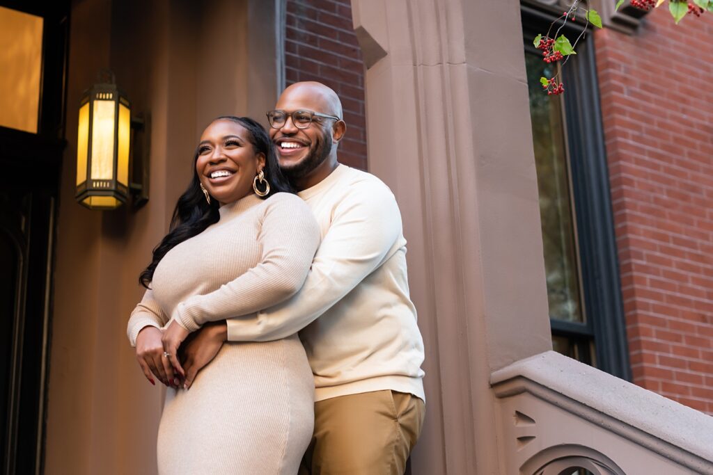 African american couple sitting on Brooklyn brownstone steps smiling