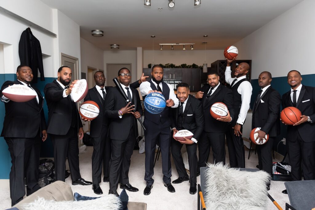 african american groom holding basketballs with his groomsmen on his wedding day