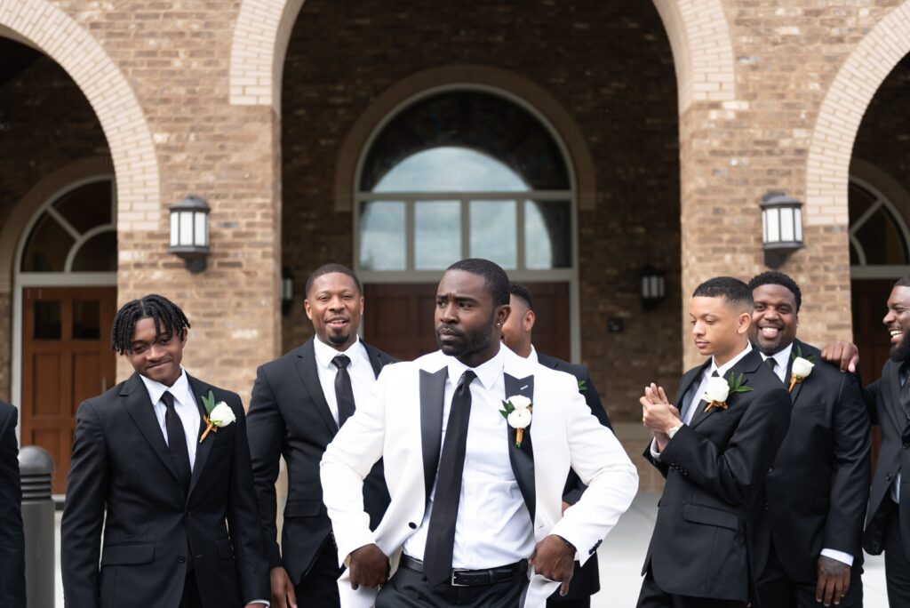 african american groom in white and black tuxedo with groomsmen in black tuxedos